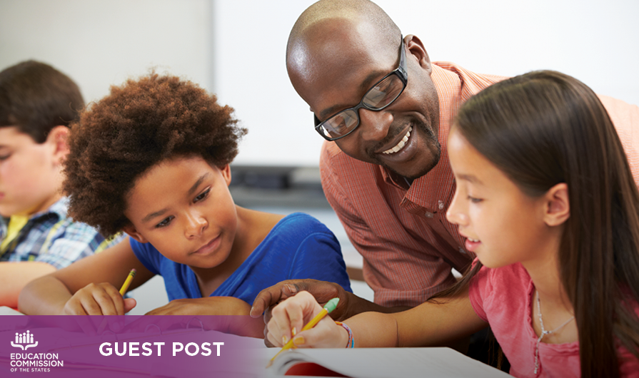 A teacher with dark brown skin and a bald hair style smiles while helping two students with a math problem. One student has brown skin and natural hair and the other has light brown skin and long, dark-brown hair. The bottom left corner of the image says “guest post.”