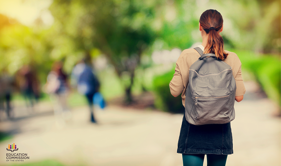 new college student walking down campus alone with backpack on